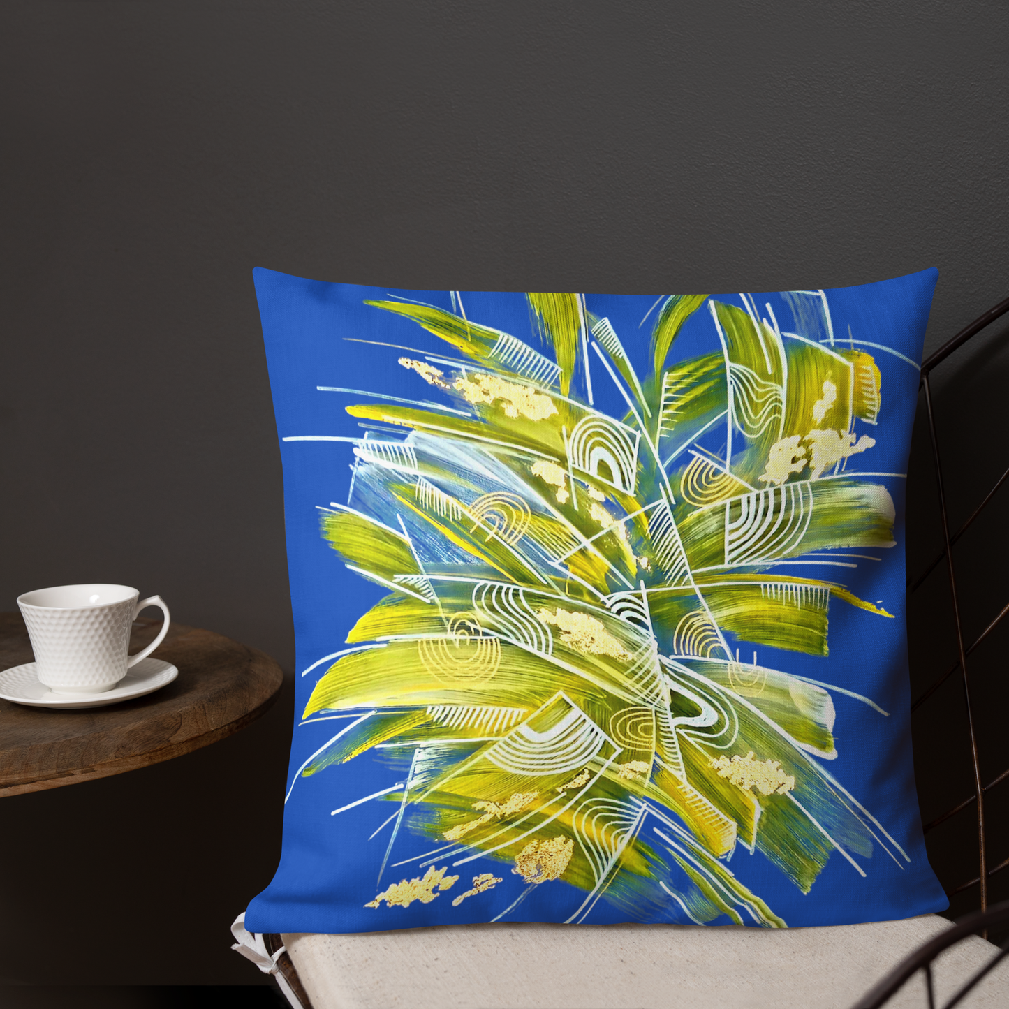 Designer Decorative blue pillow with abstract design on a chair next to a cup and saucer. For modern home and slow life