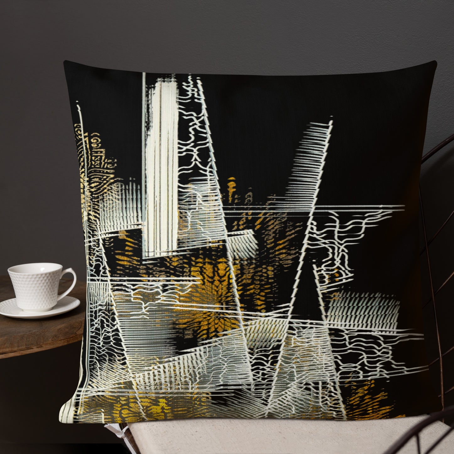 A black decorative throw pillow with a white and yellow abstract floral art print, displayed on a sofa with a white cup and saucer to the side. pillows for decoration on bed